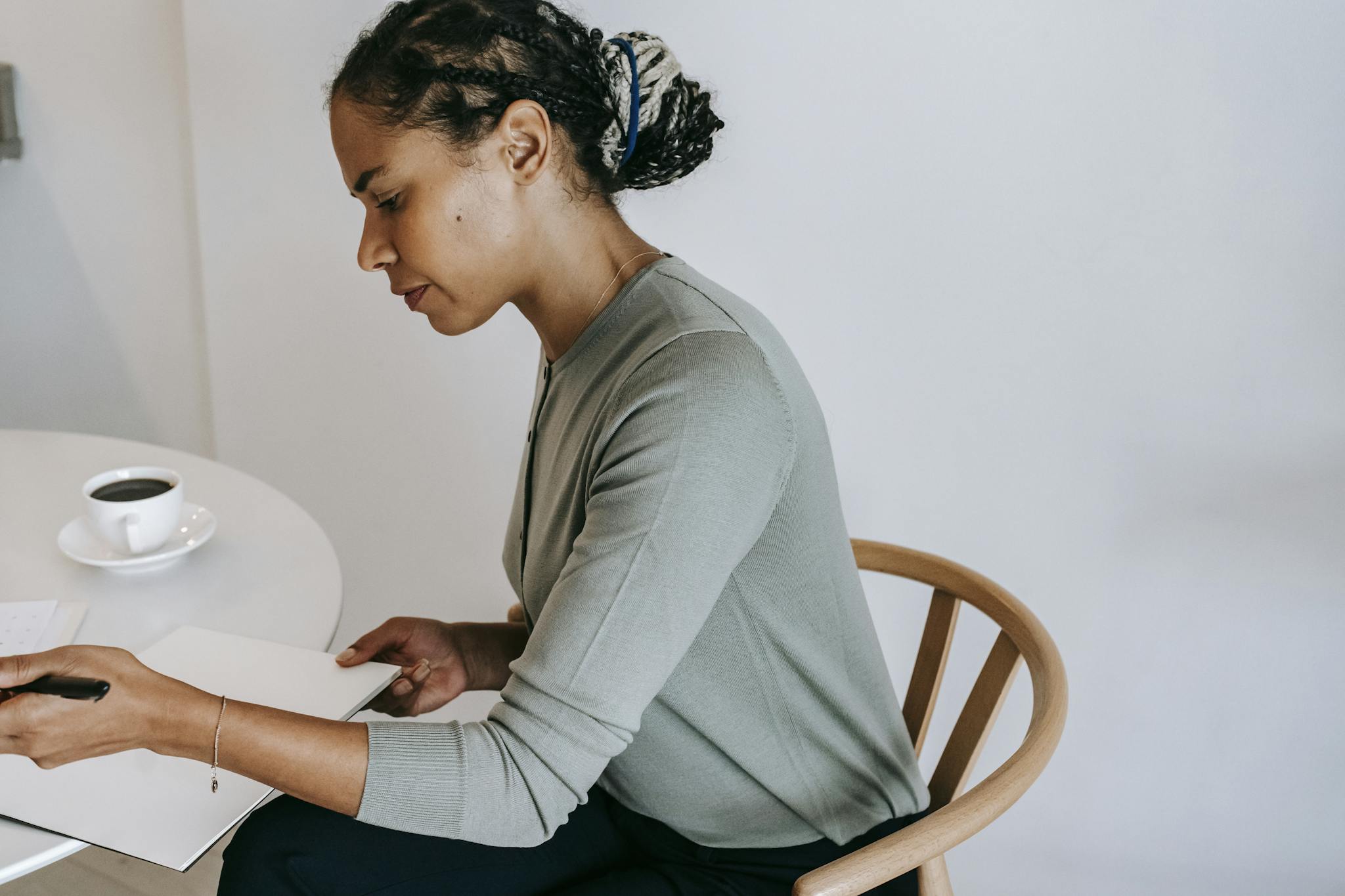 Portrait of a woman concentrating while writing in an office setting with coffee.