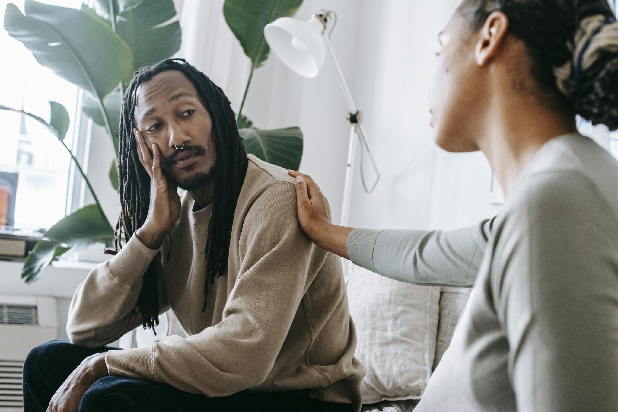 Two diverse individuals having an empathetic conversation in a cozy indoor setting.